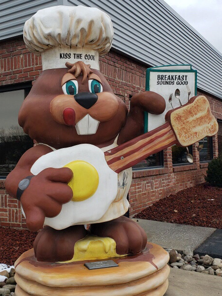 the famous Punxsy Phil statue holding a guitar made of breakfast foods with a menu and chef's hat that says "kiss the cook"